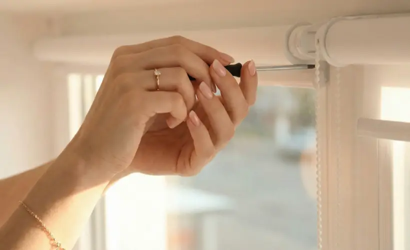 Installing a window blind mechanism with a screwdriver.
