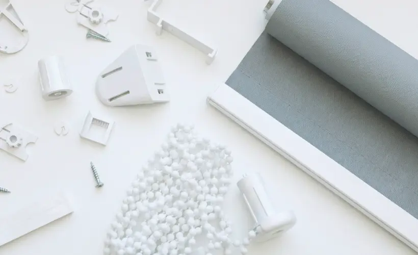 A grey fabric roller blind with the parts needed for installation.